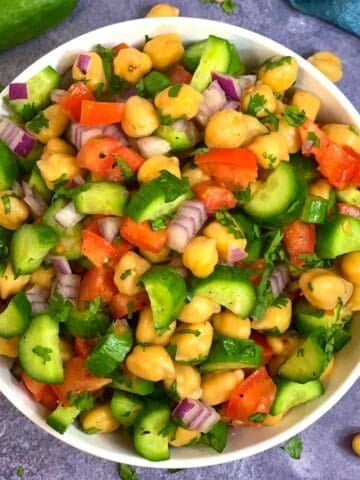 Chickpea Cucumber Tomato Salad served in a bowl with whole cucumber on side