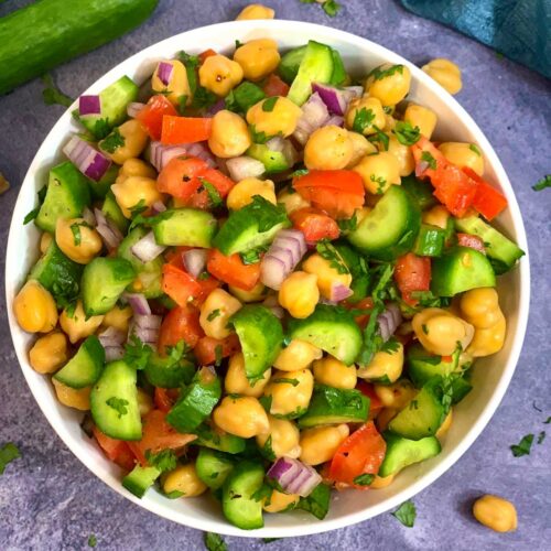 Chickpea Cucumber Tomato Salad served in a bowl with whole cucumber on side