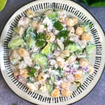 chickpea salad with yogurt dressing served on a plate and lemon wedge on the side