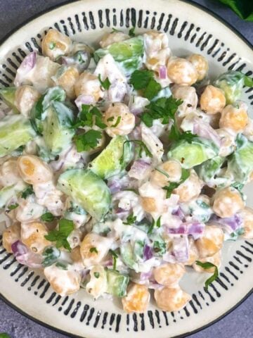 chickpea salad with yogurt dressing served on a plate and lemon wedge on the side