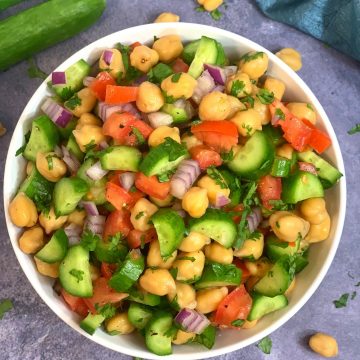 garbanzo beans salad served in a white bowl with persian cucumber on the side
