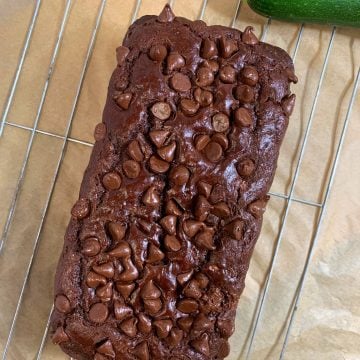 chocolate healthy zucchini bread on a wirestand with zucchini on side