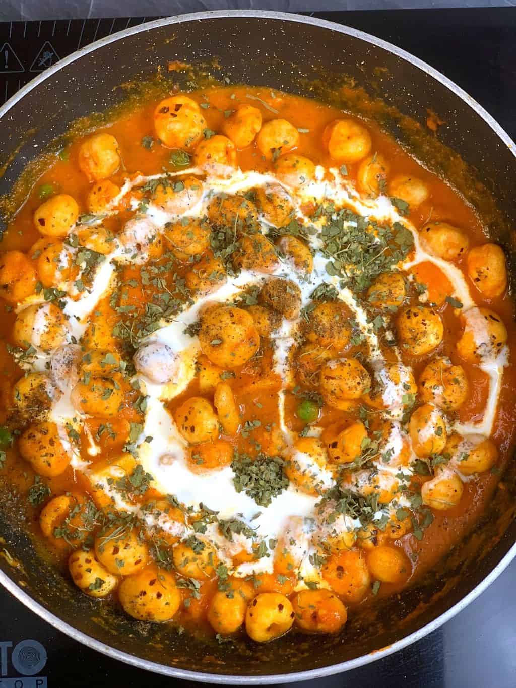 garnish phool makhana paneer matar curry with cream, kasuri methi and garam masala.