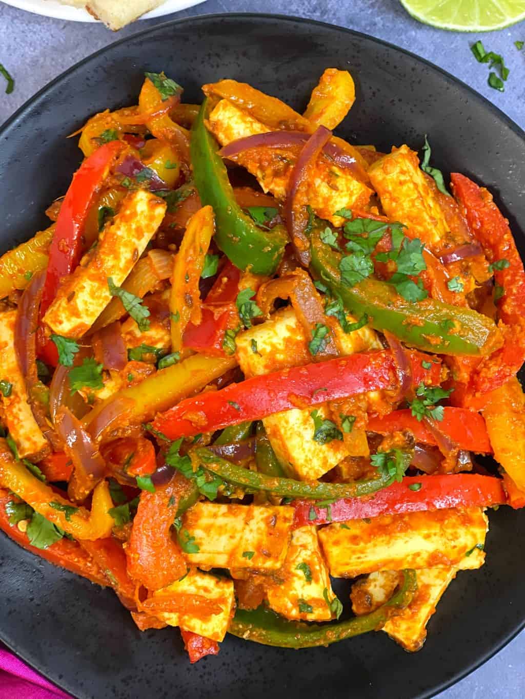 paneer stir fry with bell peppers served in a plate garnished with coriander leaves