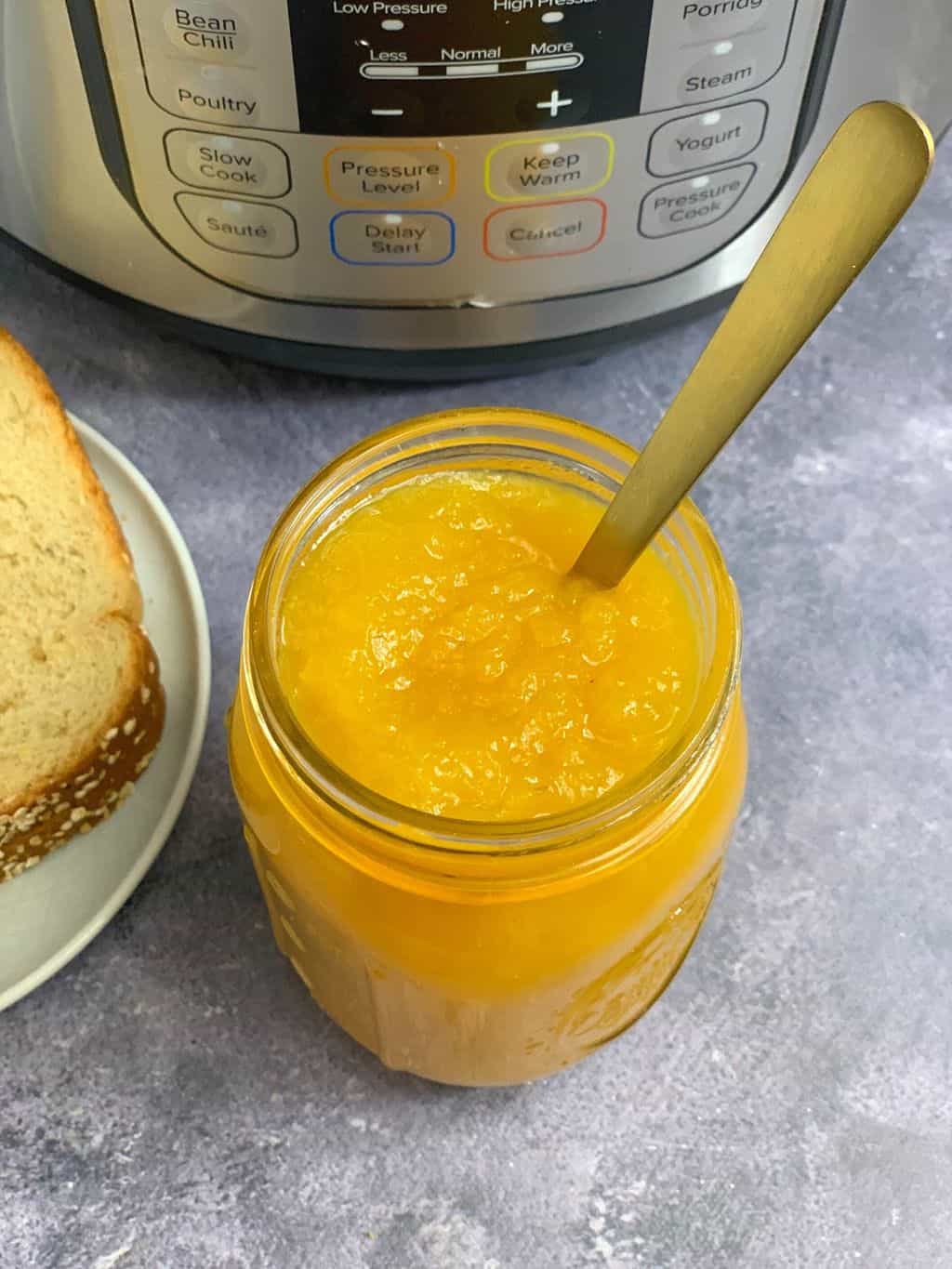 pineapple jam served in a mason jar with a spoon and instant pot on the side