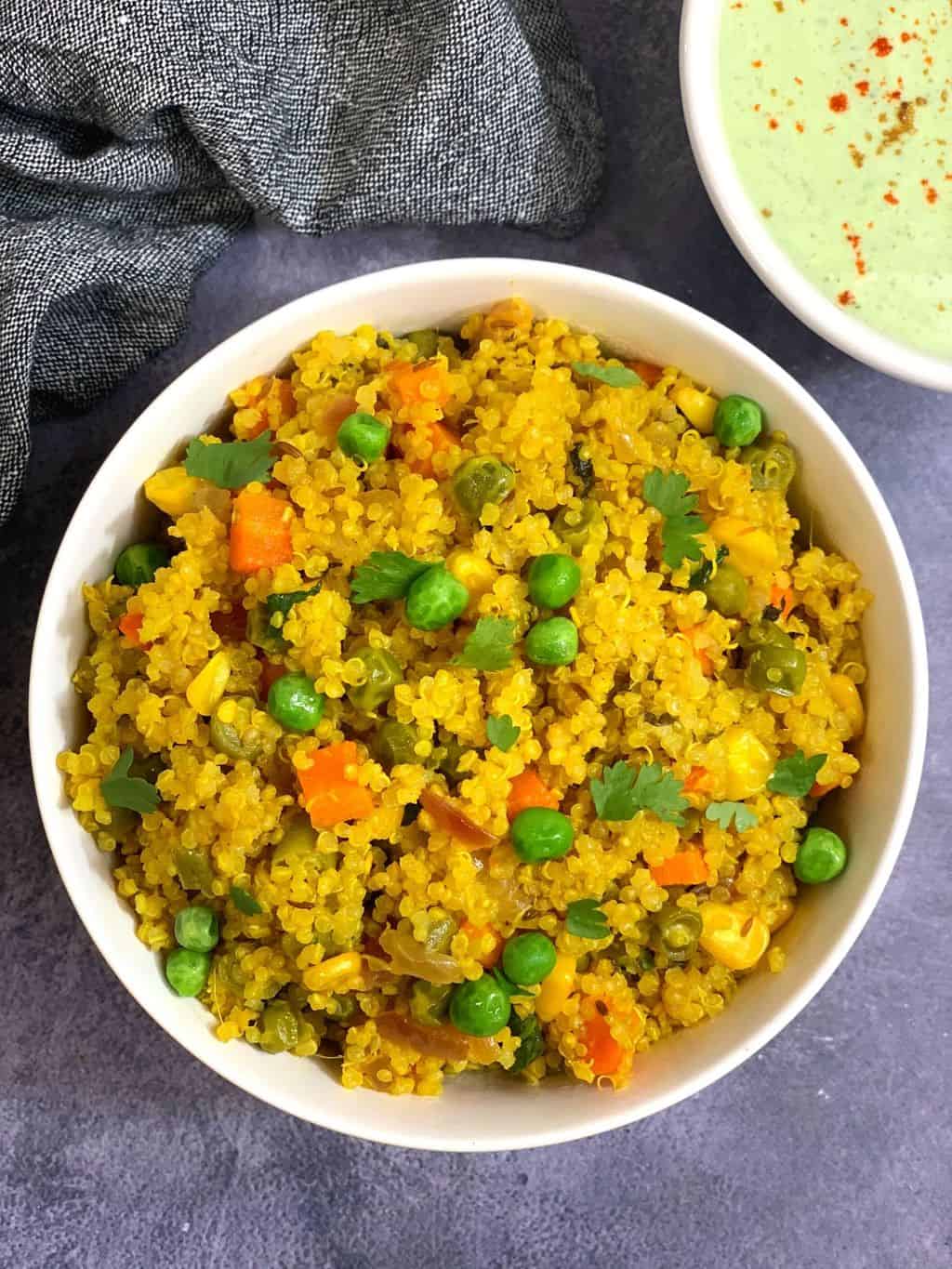 instant pot vegetable quinoa pulao/pilaf served in a white bowl with raita on side