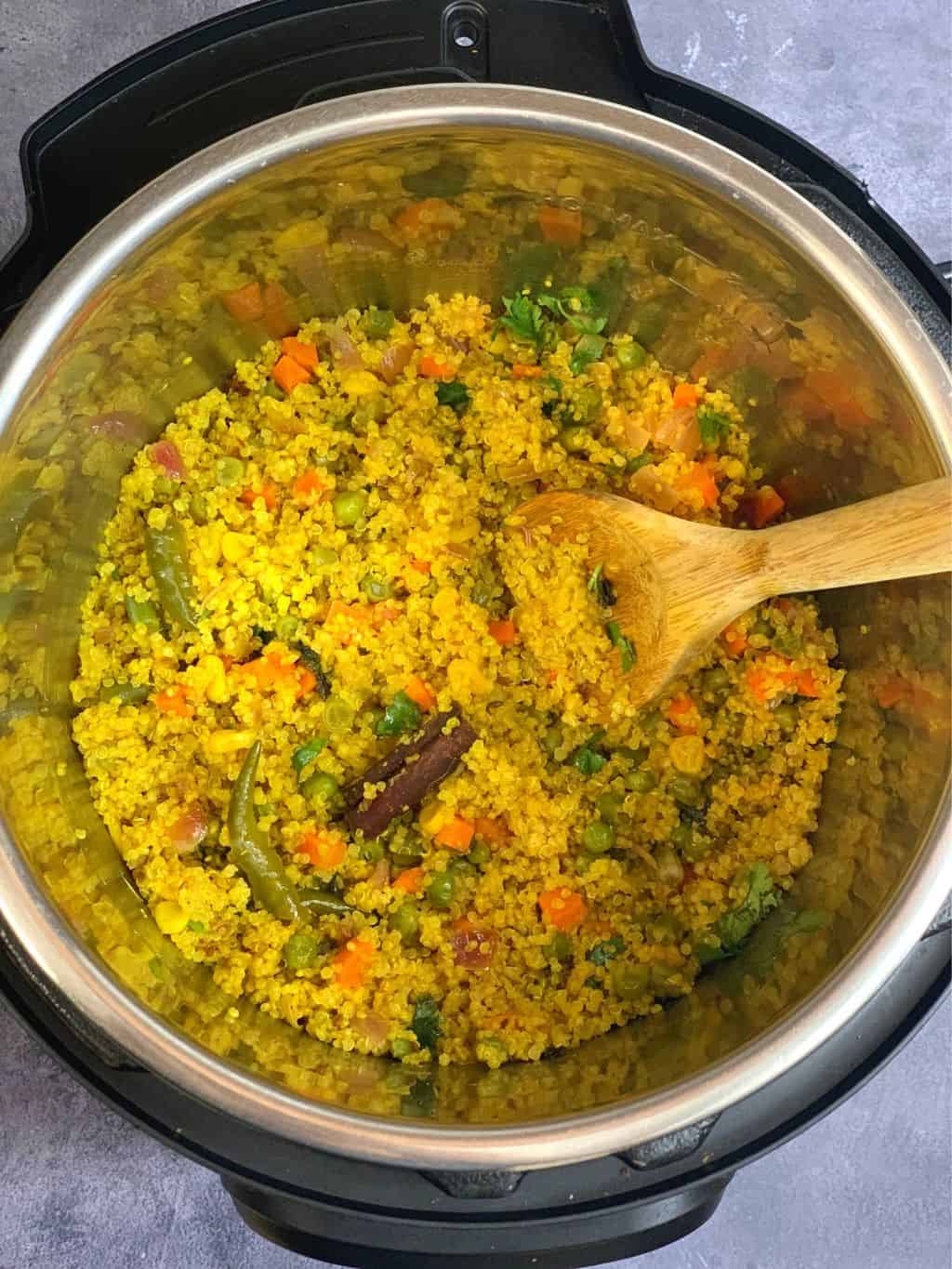 Vegetable Quinoa Pilaf in instant pot insert with a wooden spoon
