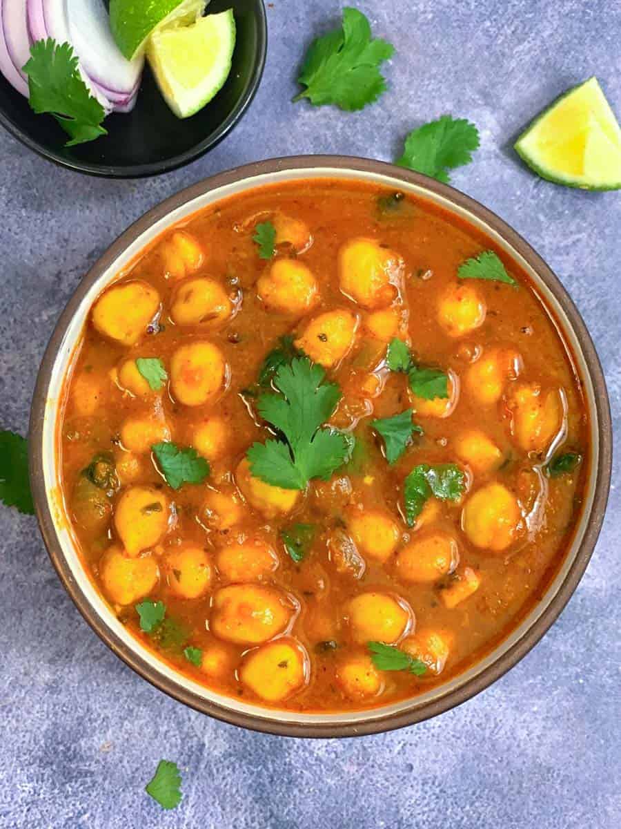 indian chickpea curry recipe made in the instant pot served in a black bowl with onion and lemon wedges on side