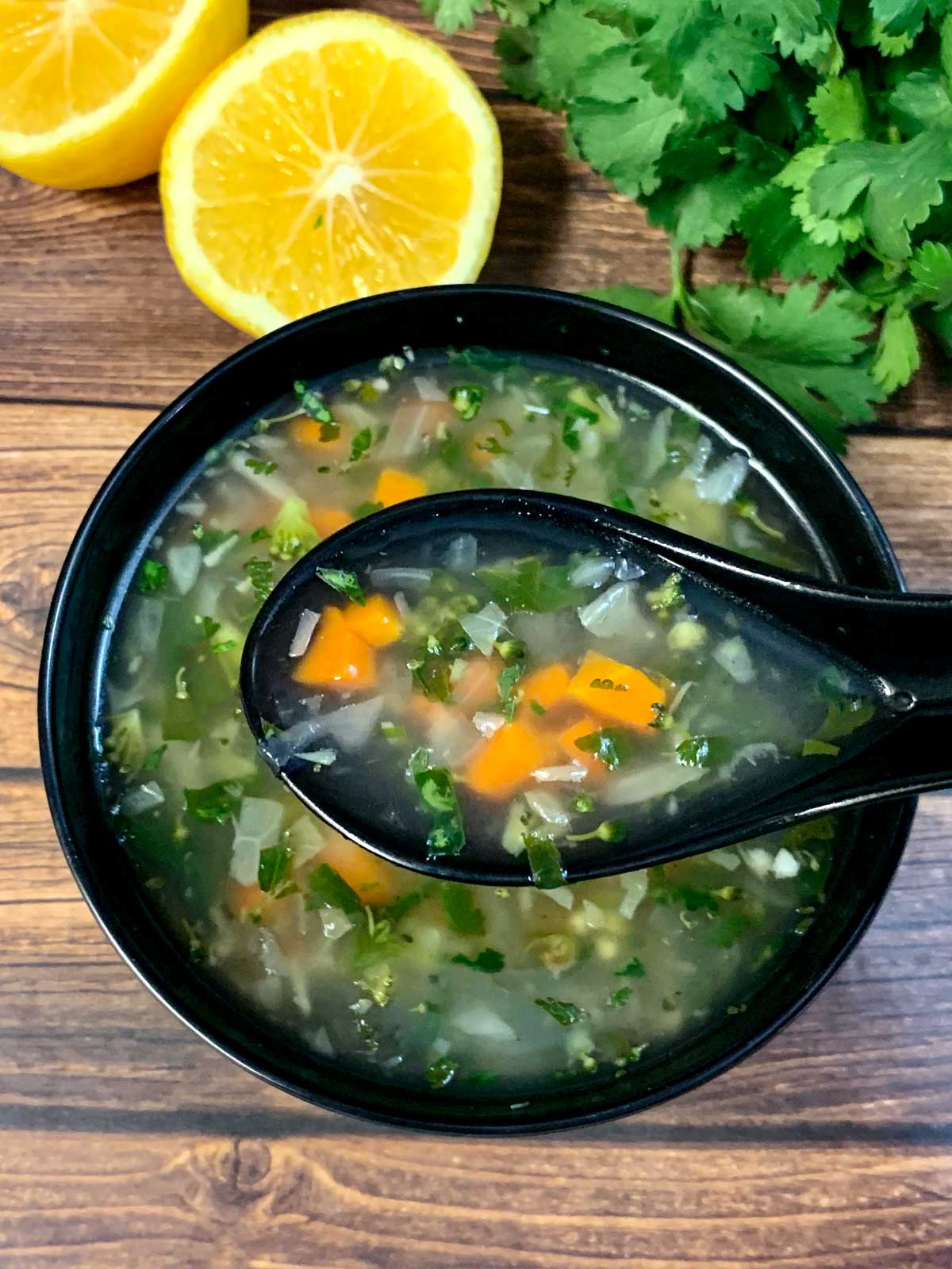 lemon coriander soup served in a bowl with lemon and cilantro on side