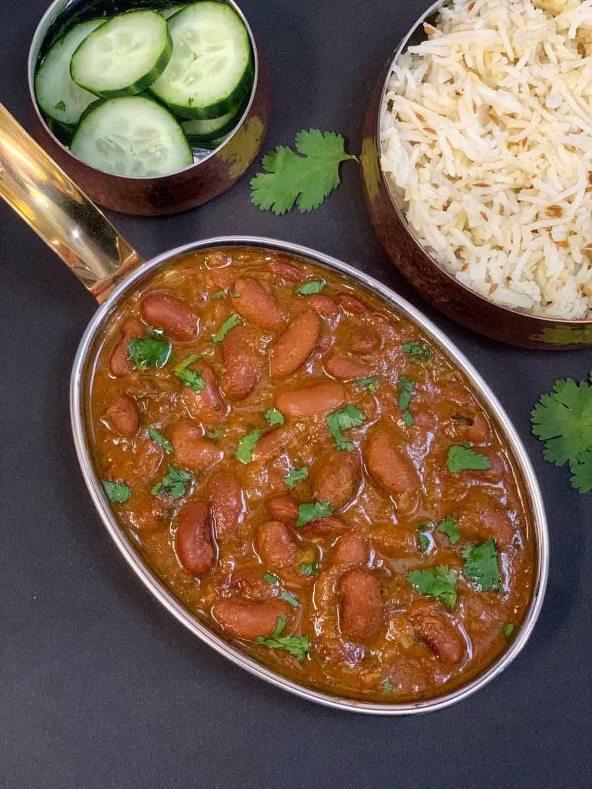 Punjabi Rajma Masala served in a serving bowl with cucumbers and jeera rice on the side