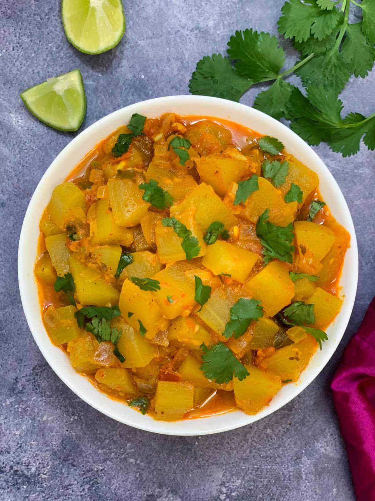 lauki sabji/bottle gourd curry served in a bowl garnished with coriander and lemon wedges and coriander leaves on the side