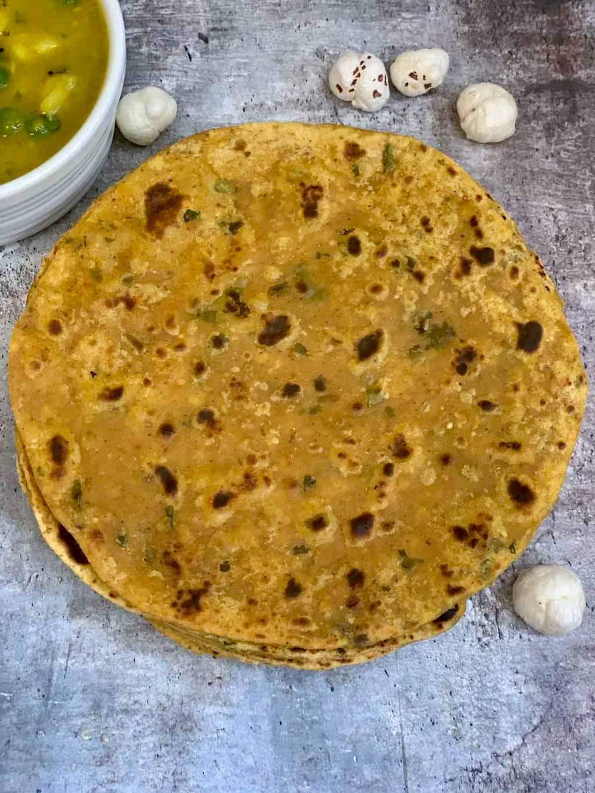 Phool Makhana Paratha served on a plate with curry on the side