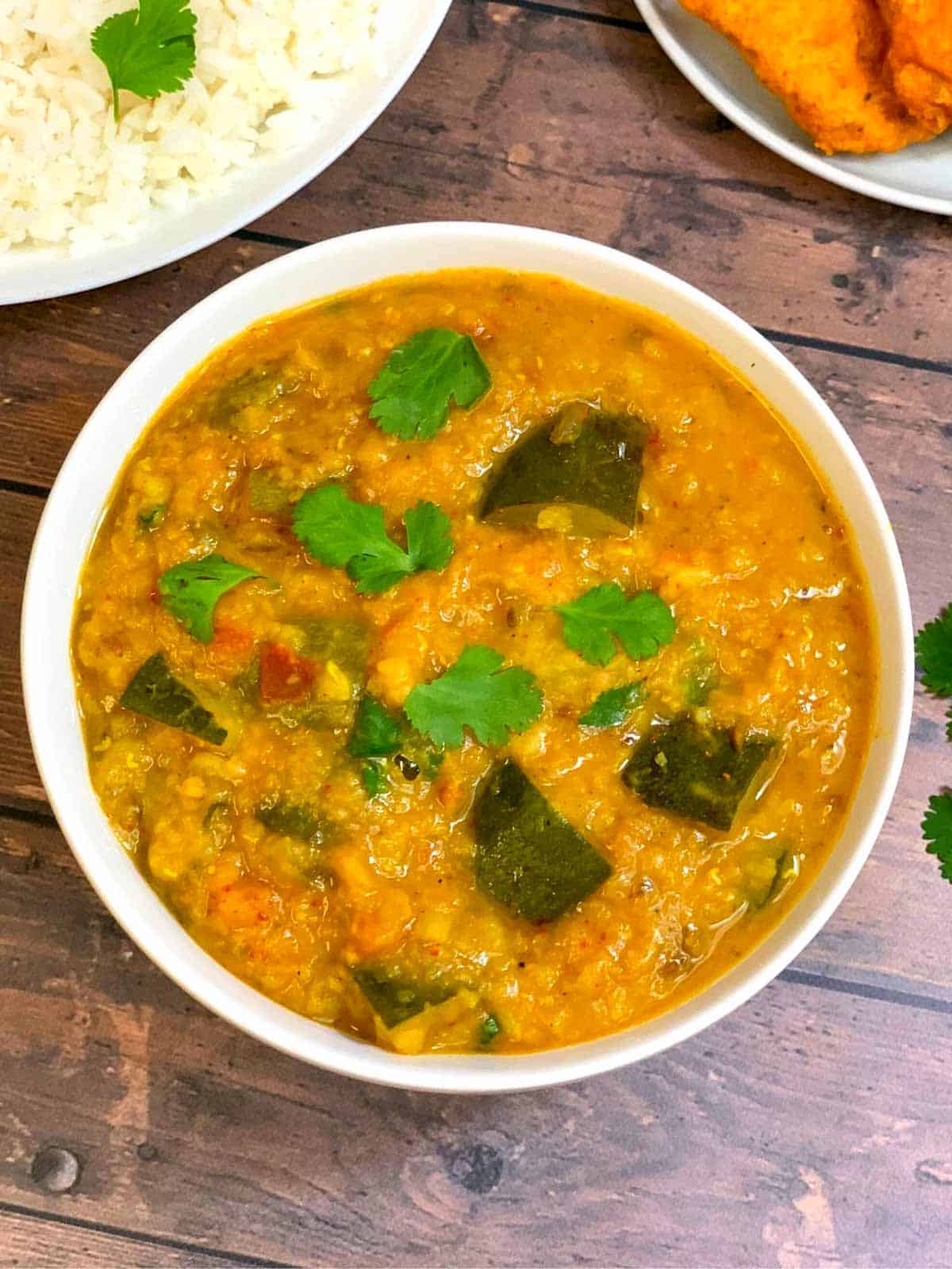 zucchini dal served in a bowl garnished with cilantro and served with a side of steamed rice