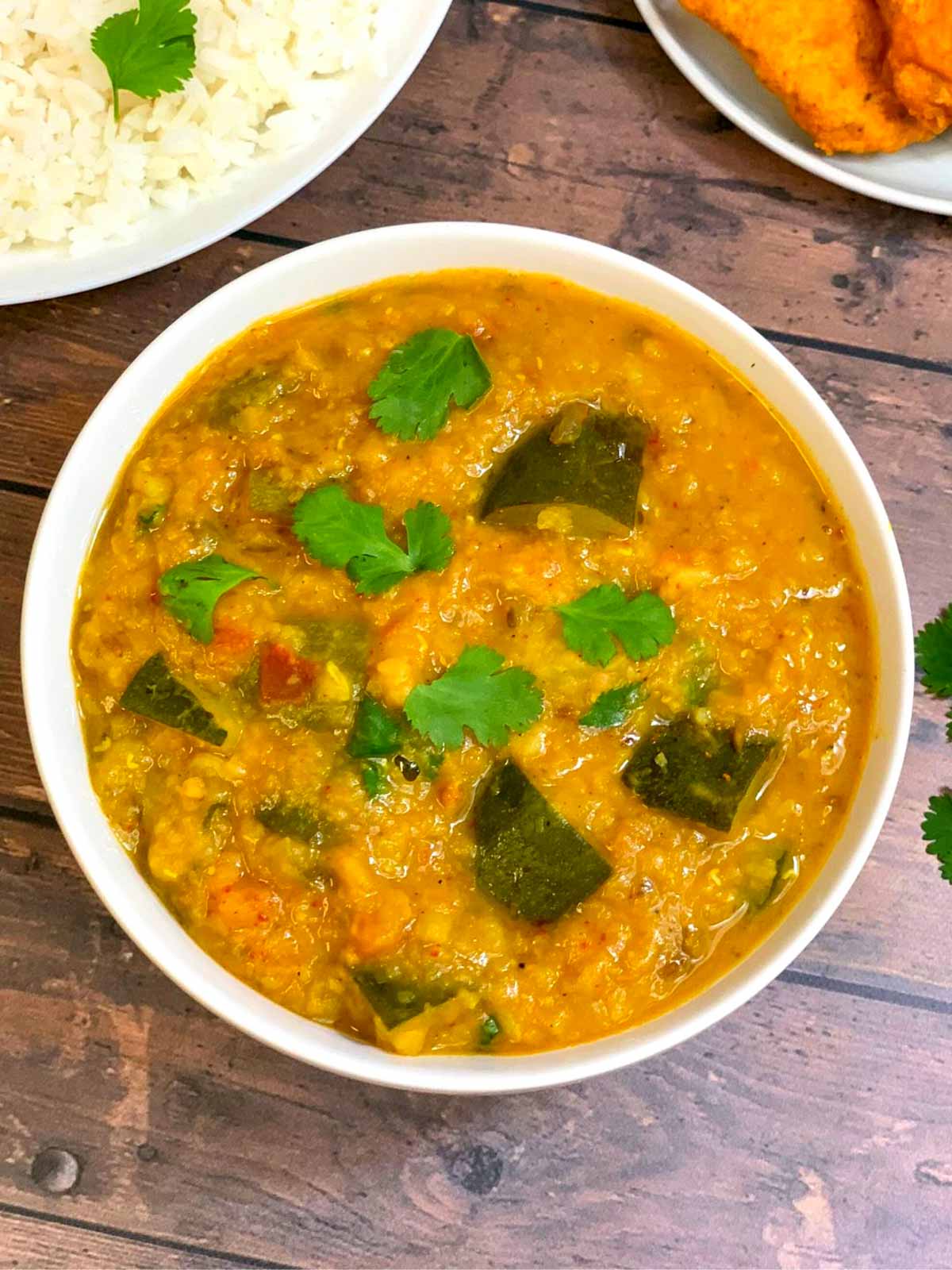 zucchini dal served in a bowl garnished with cilantro and served with a side of steamed rice
