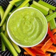 Creamy Avocado Cilantro Dip served in a bowl with vegetable sticks on the side