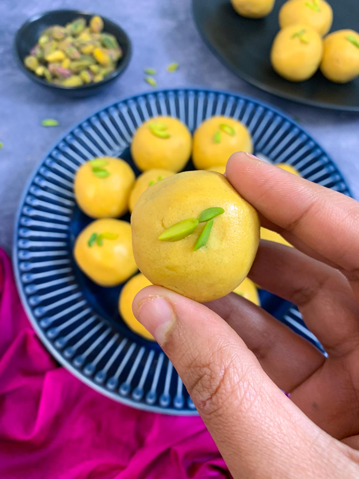 besan ladoo garnished with pistachio held in a hand