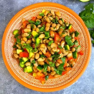 Peanut vegetable salad served in a plate with cilantro on the side