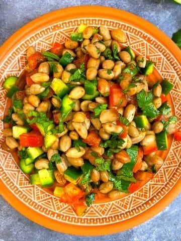 Peanut vegetable salad served in a plate with cilantro on the side