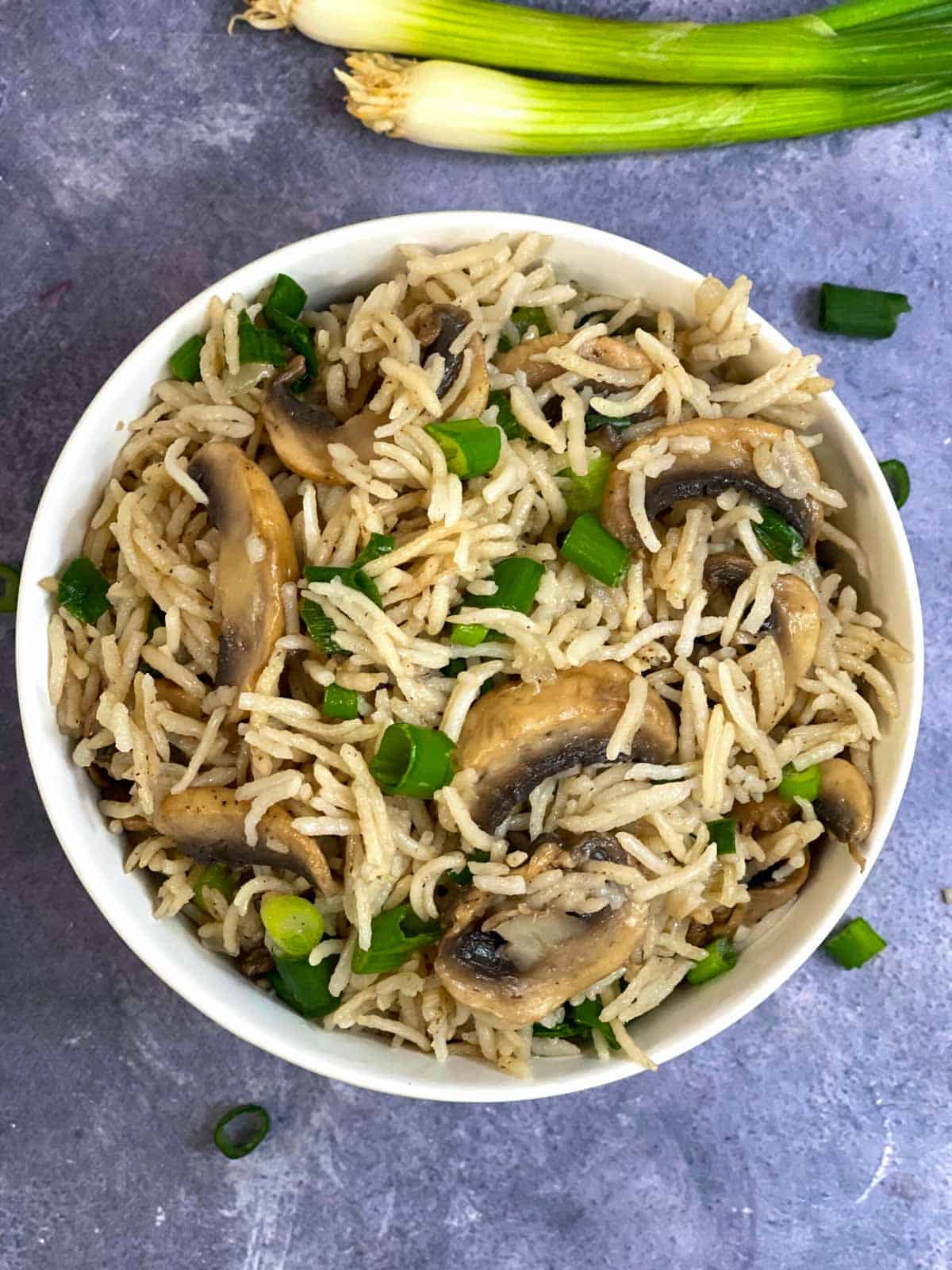 mushroom pilaf in a bowl garnished with green onions