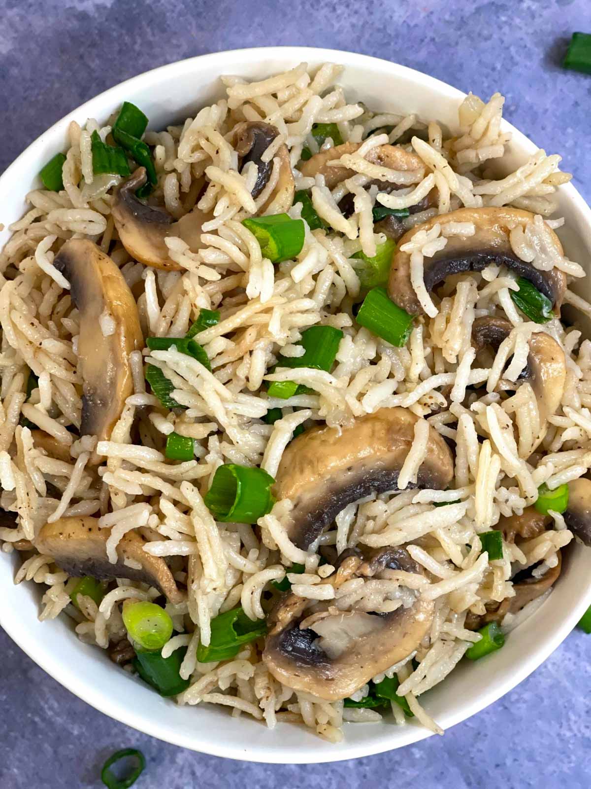 mushroom rice served in a bowl with green onions on the side