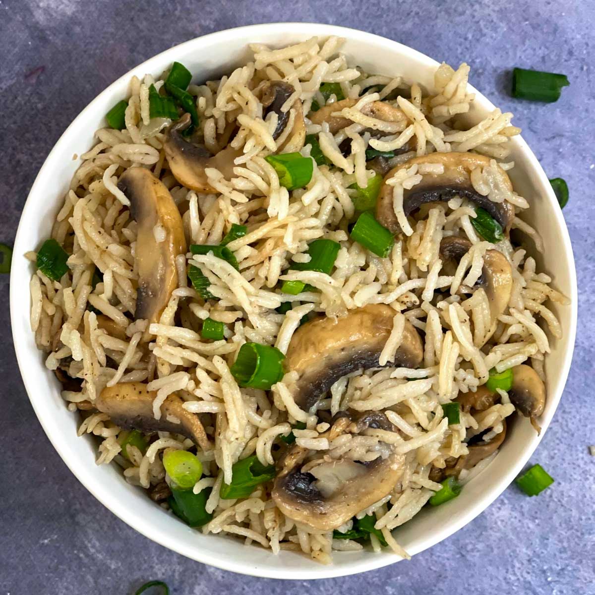 mushroom rice pilaf served in a bowl garnished with spring onions