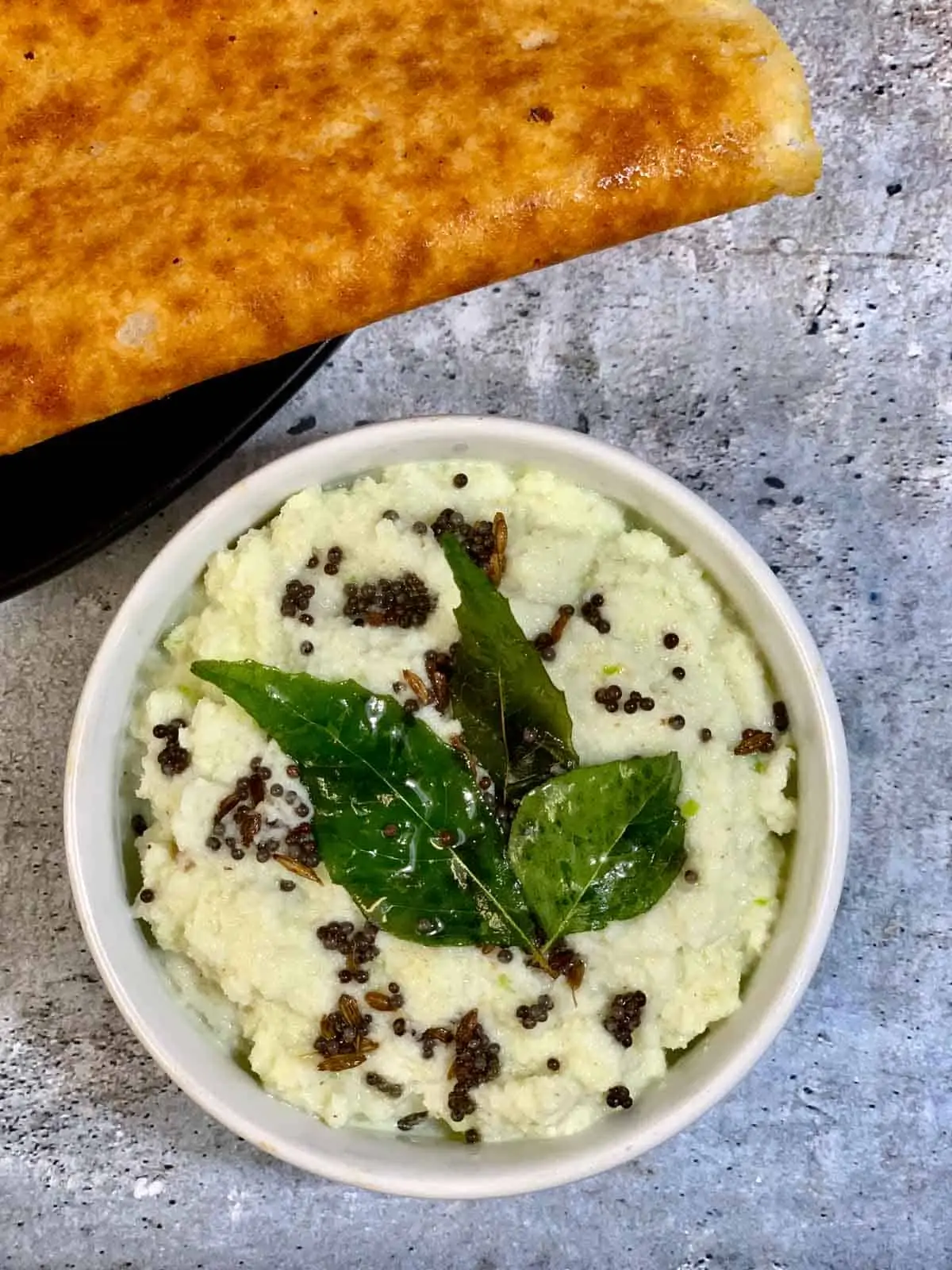 keto coconut chutney served in a bowl with tempering on the top with side of almond flour dosa