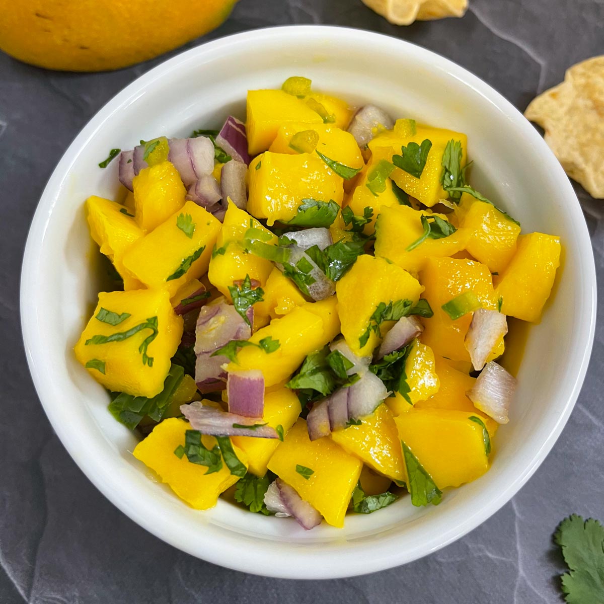 mango salsa served in a bowl with chips on the side.