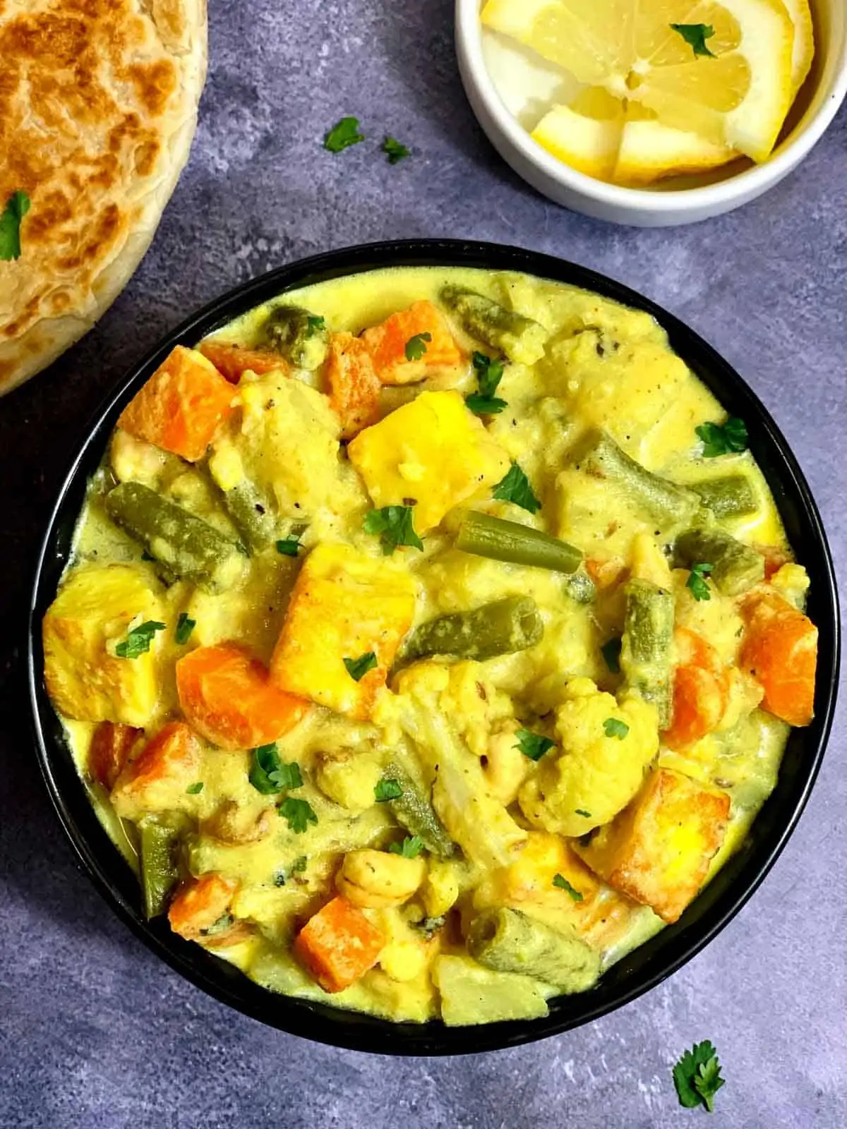 Restaurant Style Navratan Korma/kurma made in the instant pot pressure cooker served in a black bowl and paratha on side