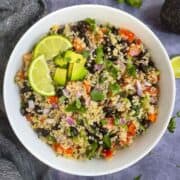 Quinoa Black Bean salad served in a bowl with lemon wedges and diced avocados on the top
