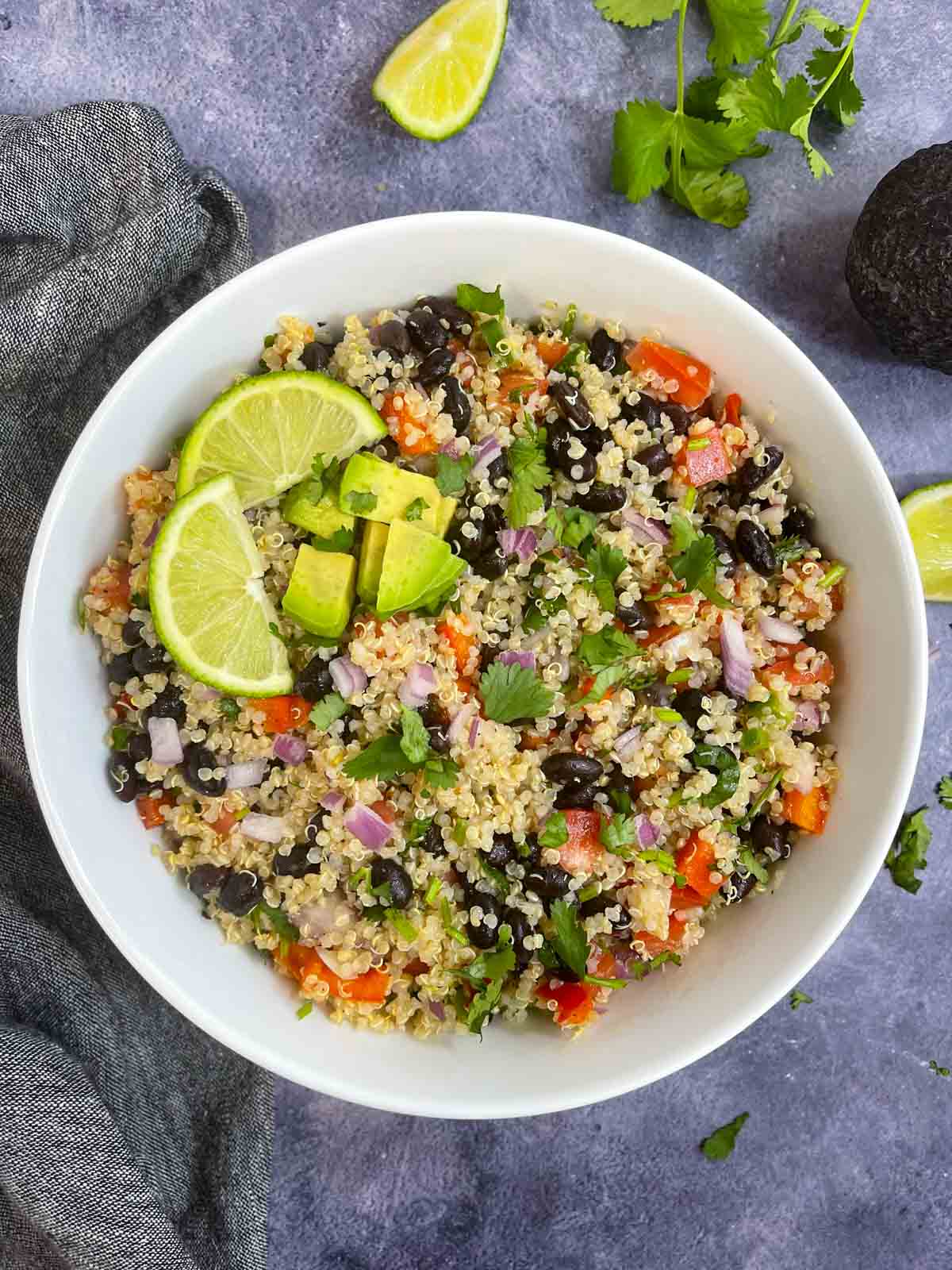 Quinoa Black Bean salad served in a bowl with lemon wedges and diced avocados on the top