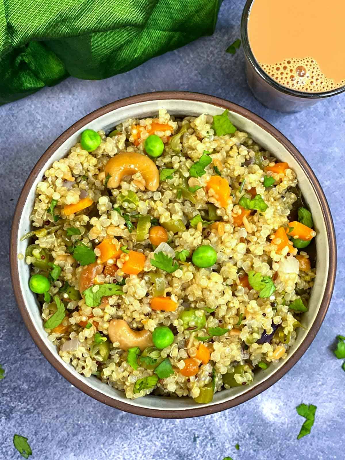 vegetable quinoa upma served in a bowl with tea on the side