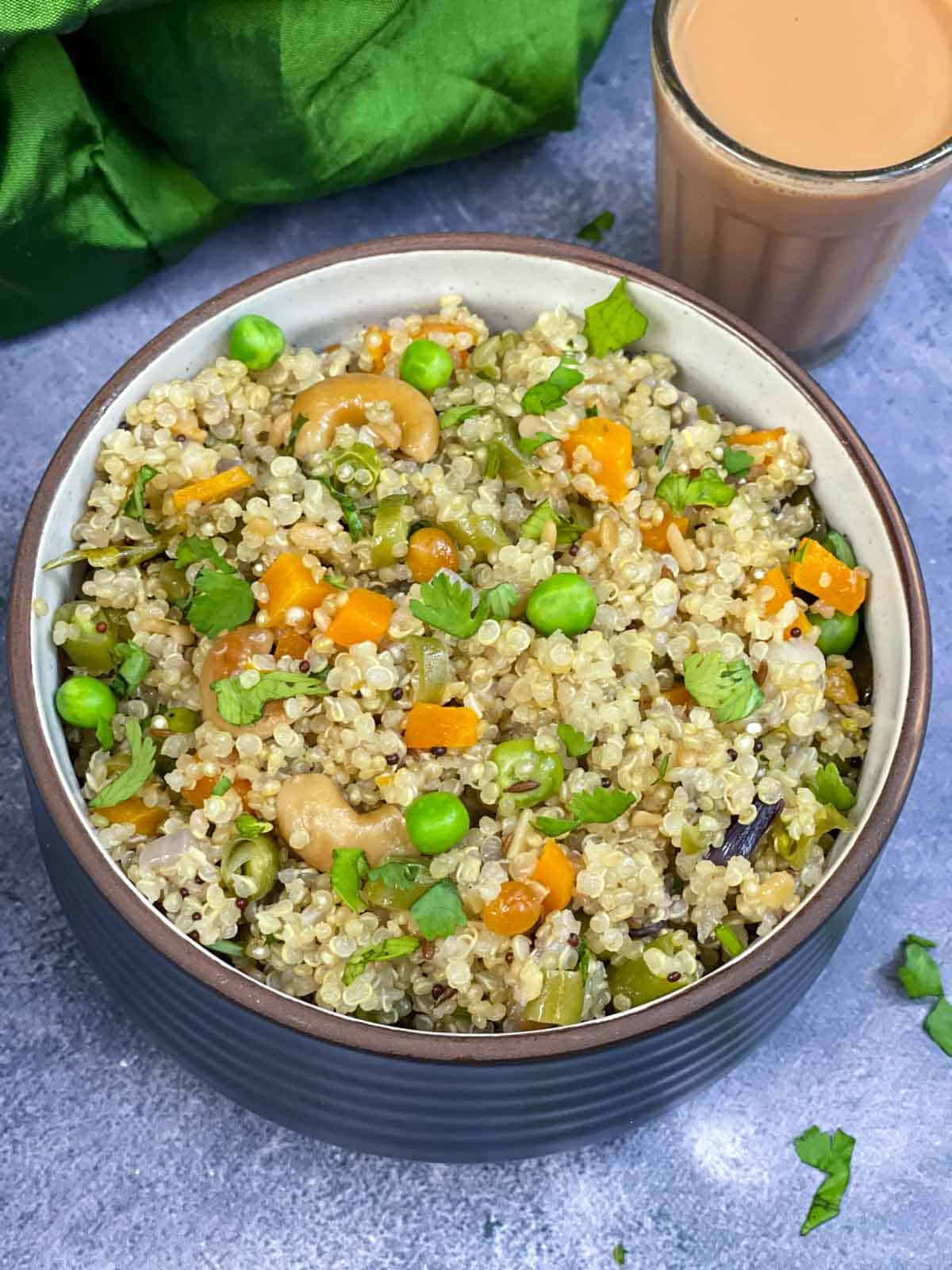 quinoa upma served in a bowl with masala chai on the side