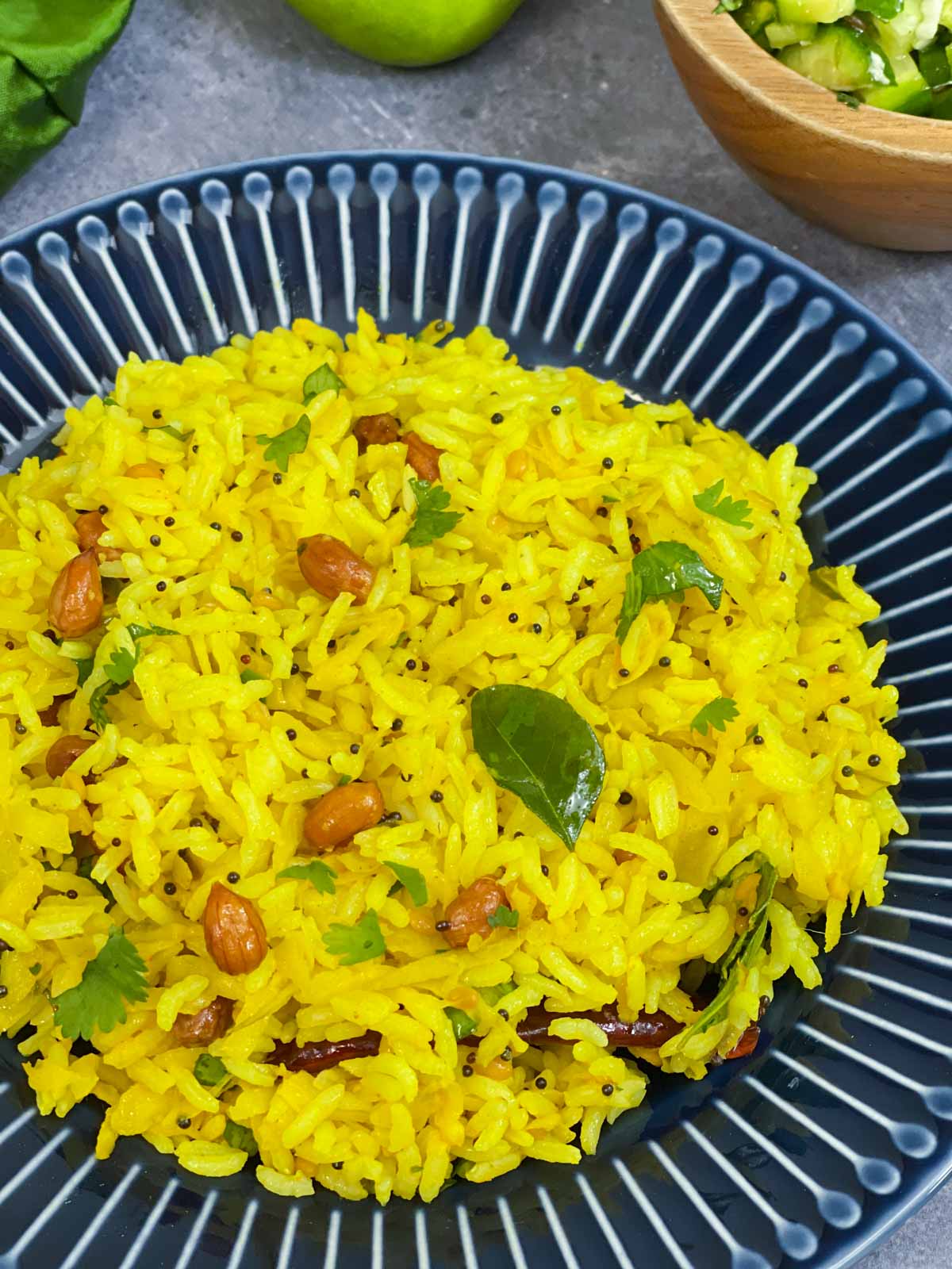 mavinakayi chitranna served in a plate with lemon and cucumber salad on the side