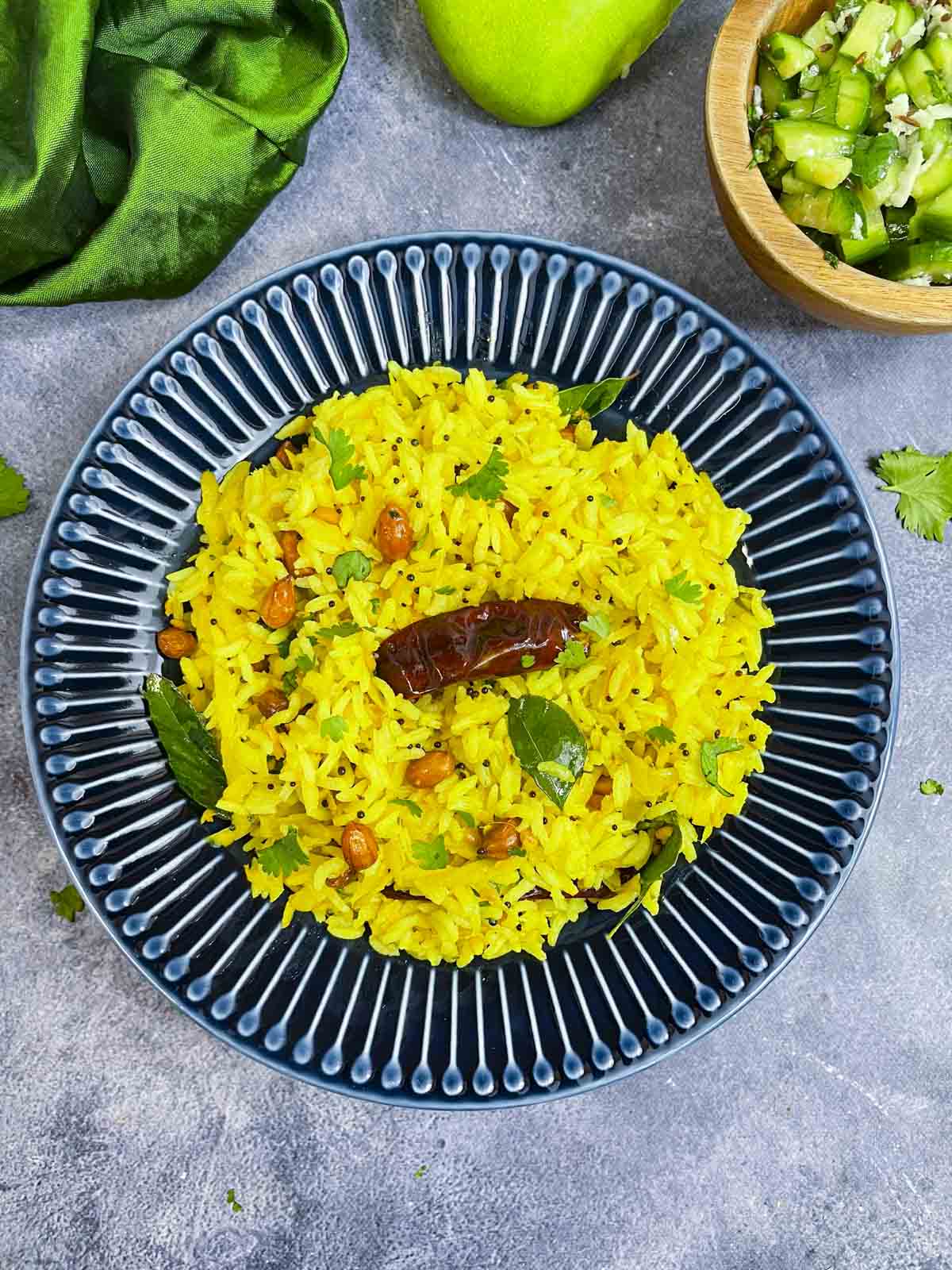 Raw Mango Rice served on a plate with green mango n cucumber salad on the side