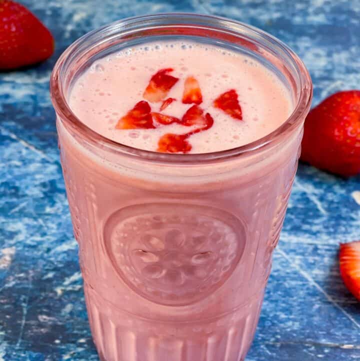 strawberry lassi served in a glass topped with chopped strawberry