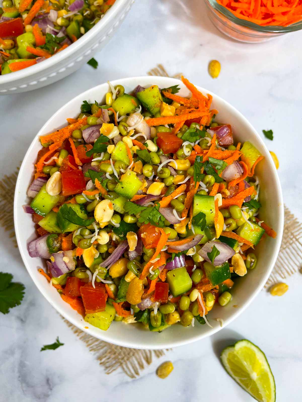 sprouted moong salad served in a bowl, with lemon wedge on the side