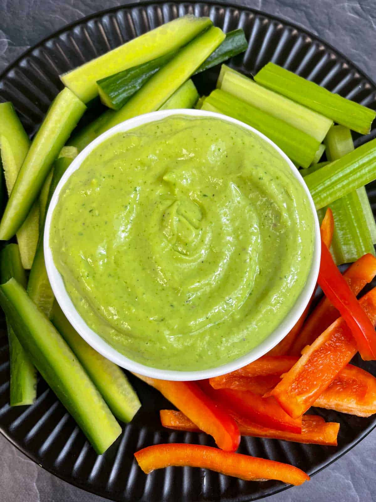 Creamy Avocado Cilantro Dip served in a bowl with vegetable sticks on the side