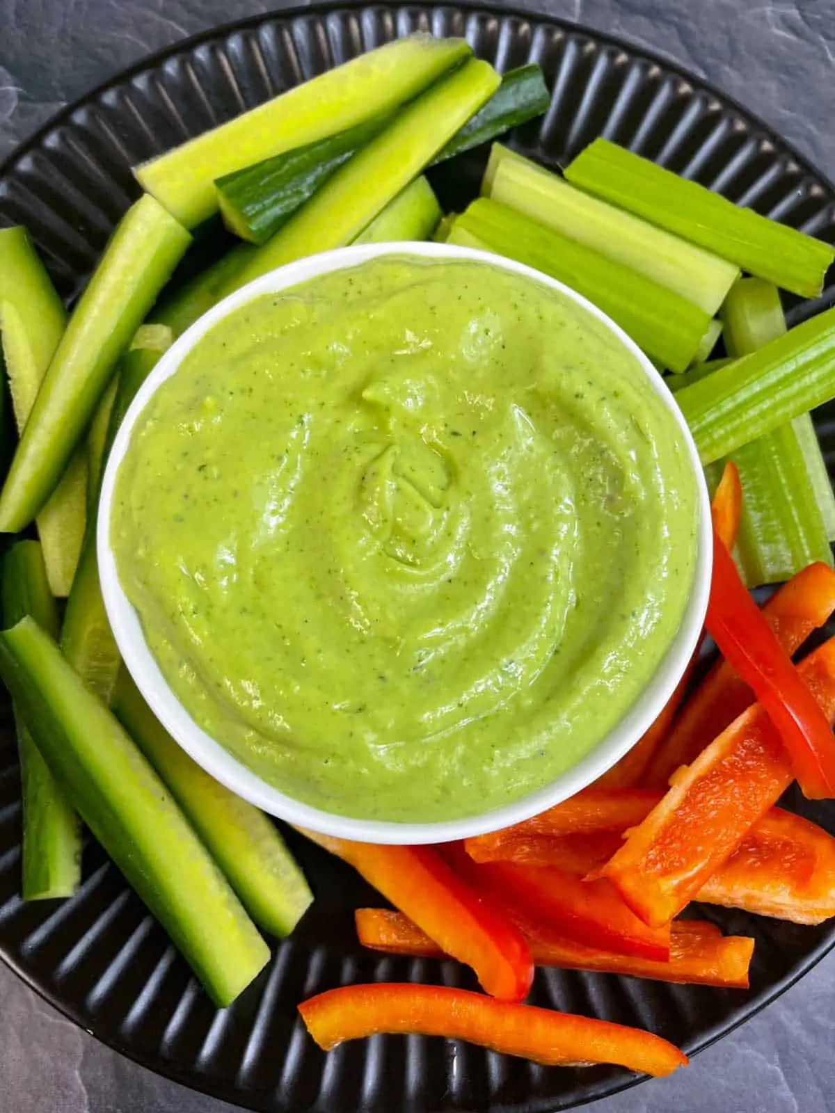 Creamy Avocado Cilantro Dip served in a bowl with vegetable sticks on the side