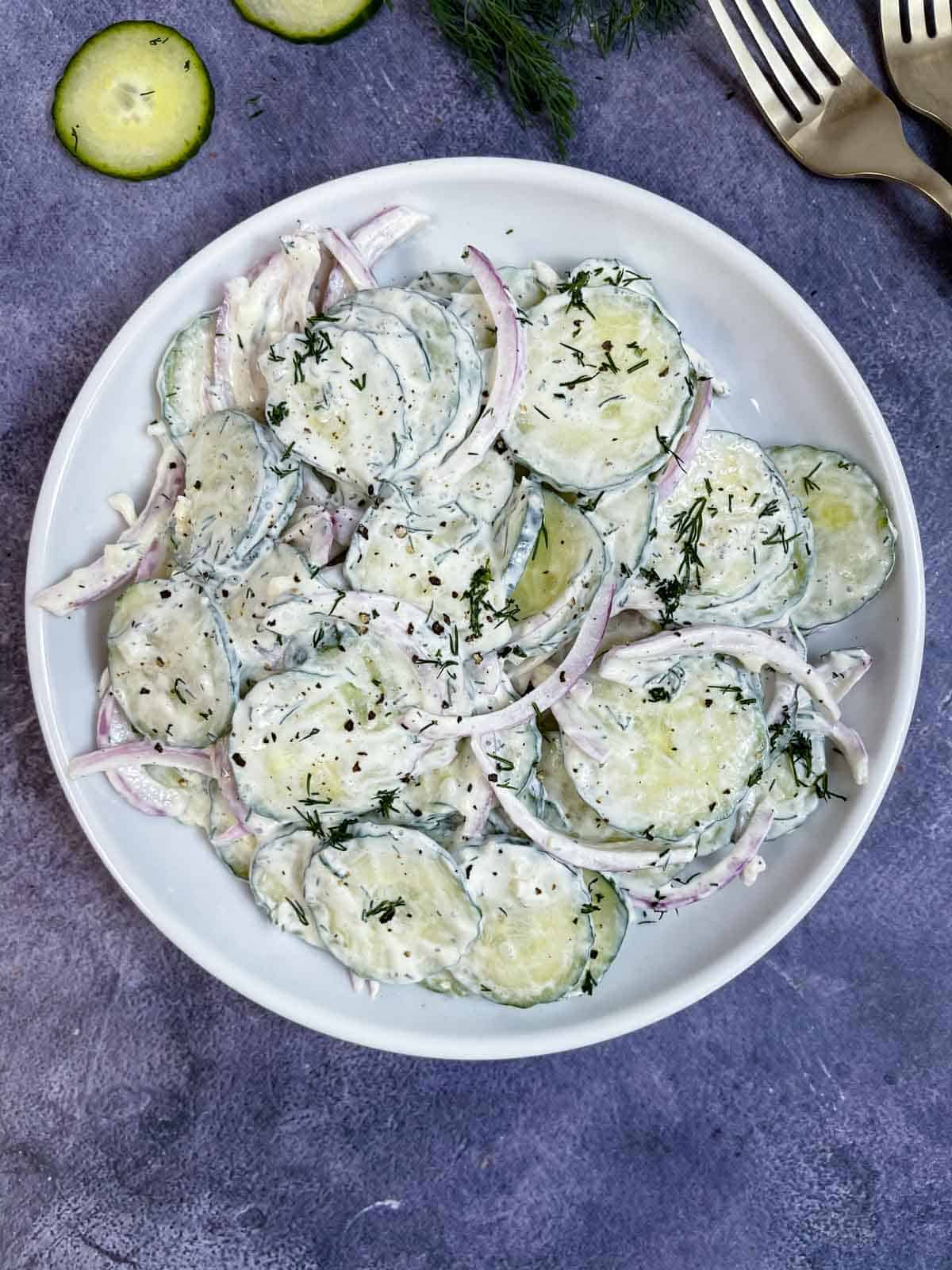 creamy cucumber salad served on a plate with forks on the side