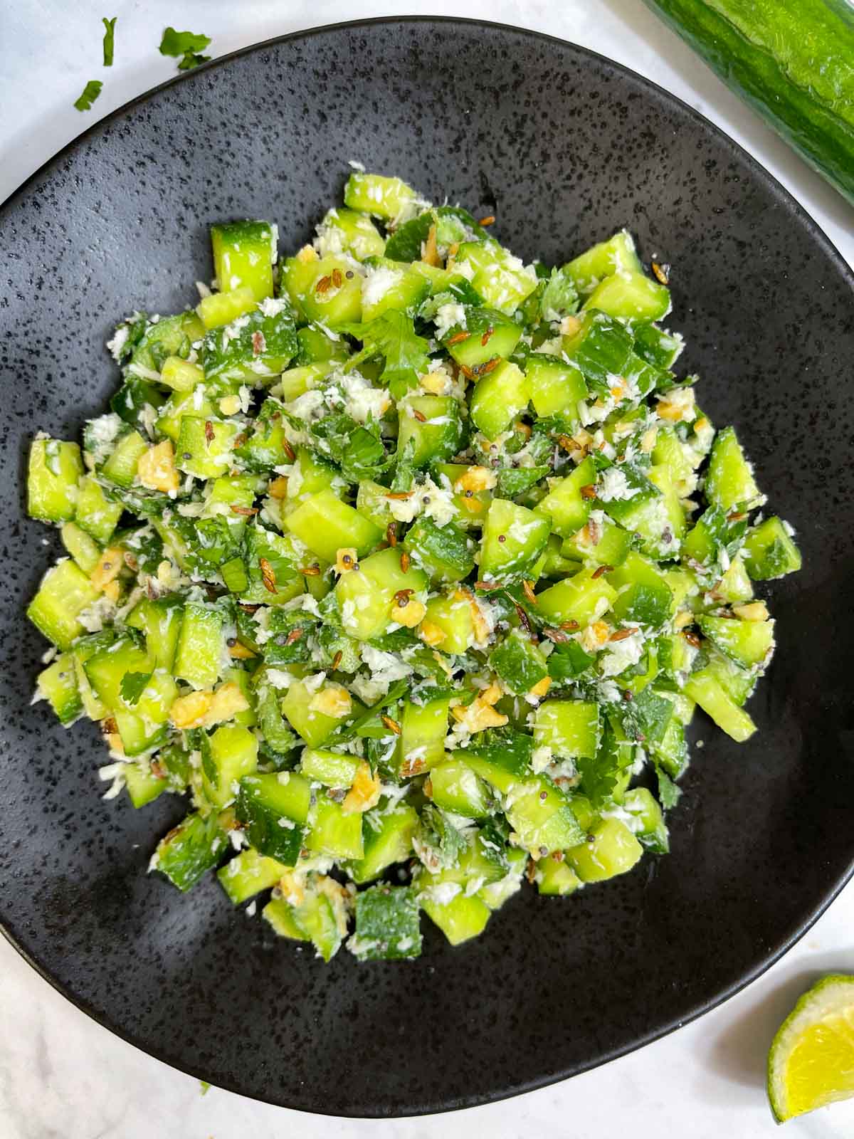 kakdi koshimbir served in a plate with lemon wedge on the side