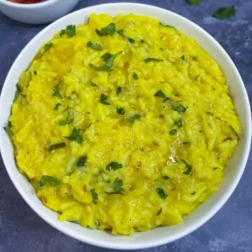 Moong Dal Khichdi served in a bowl garnished with cilantro with salad on the side