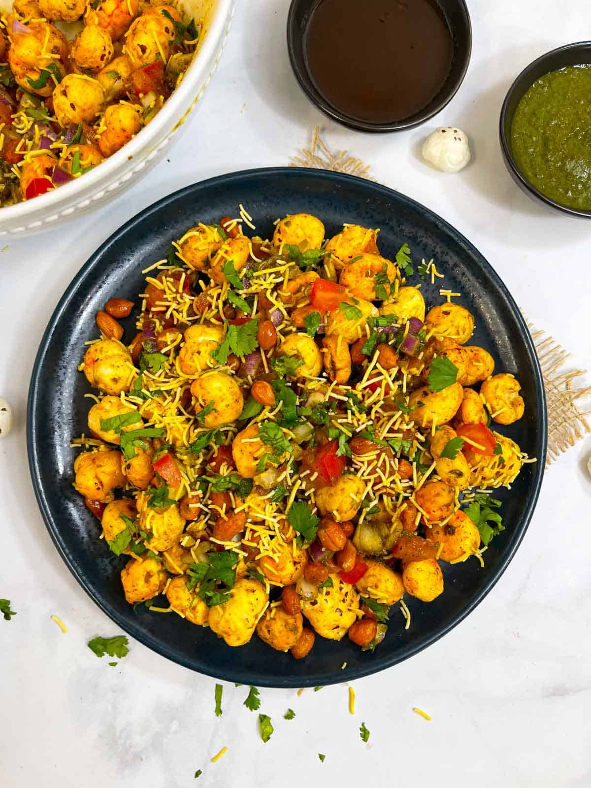 healthy Phool Makhana Bhel served in a plate garnished with cilantro with sweet and tangy chutney on side