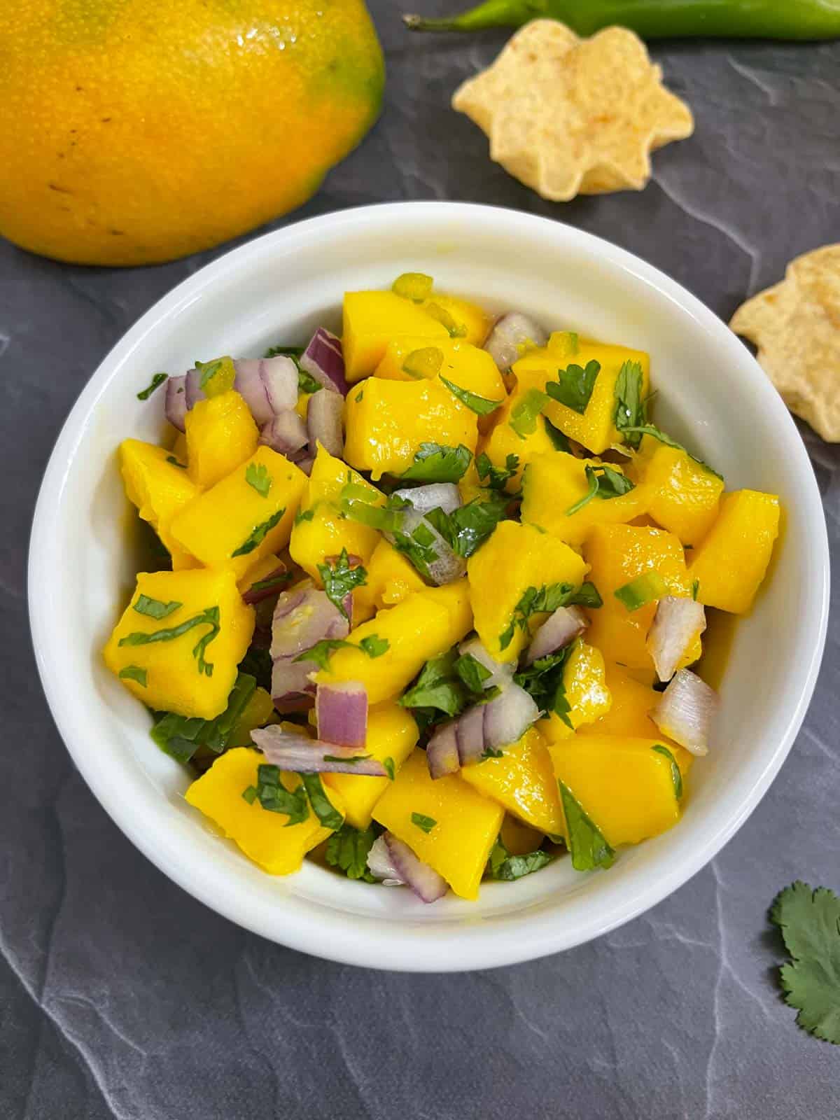 Mango salsa served in a bowl with chips on the side