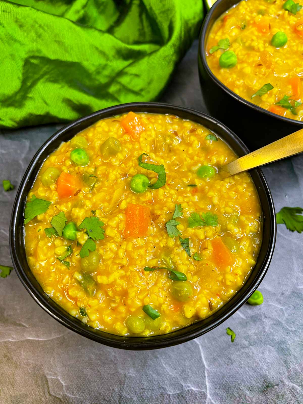 indian masala oats (Oats savory porridge ) served in a bowl with a spoon garnished with cilantro