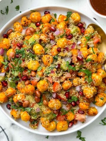 phool makhana bhel/ makhana chaat served in a plate garnished with sev and pomegranate with chutneys on the side