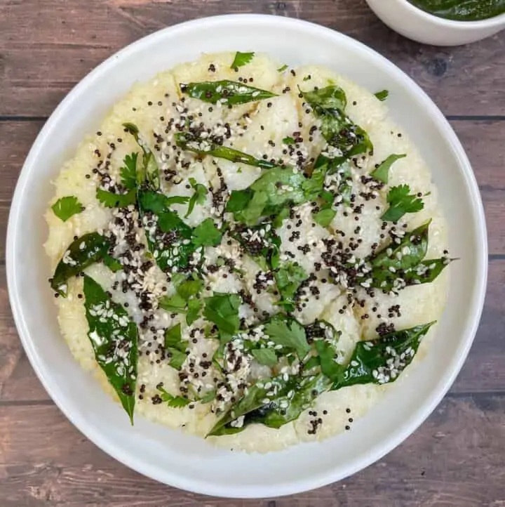 rava dhokla served on a plate garnished with cilantro with green chutney on the side