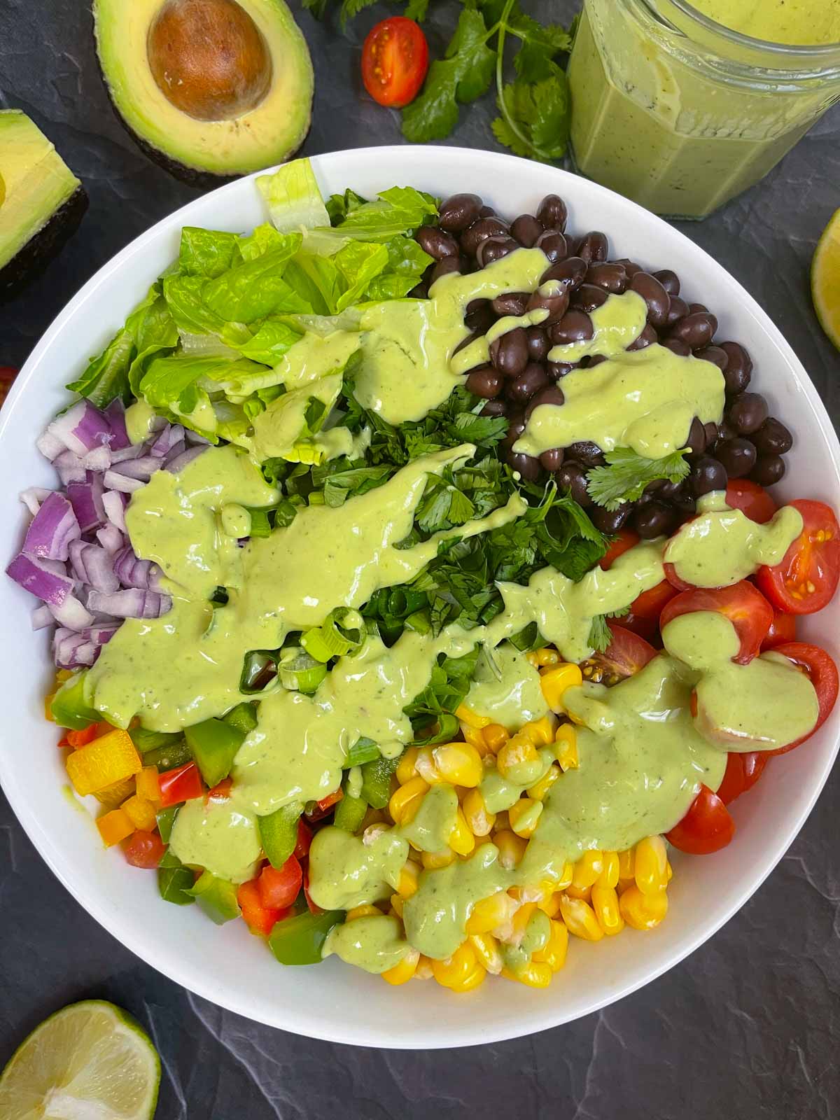 south west salad in a bowl with avocado cilantro dressing on the top