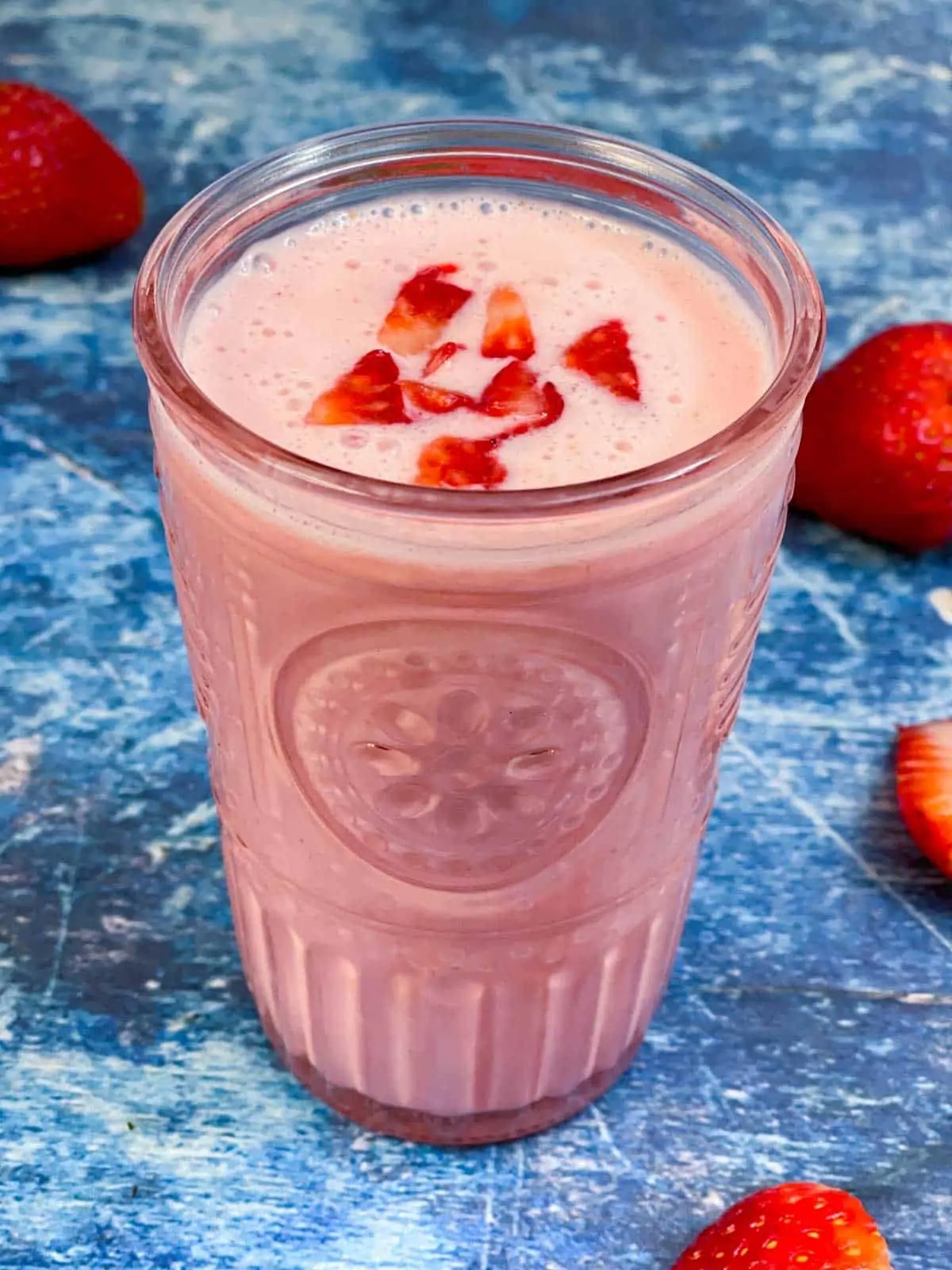 Strawberry Lassi served in a serving glass topped with chopped strawberries