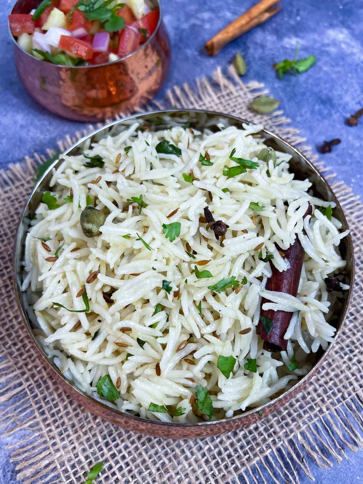 jeera rice served in a copper bowl garnished with cilantro