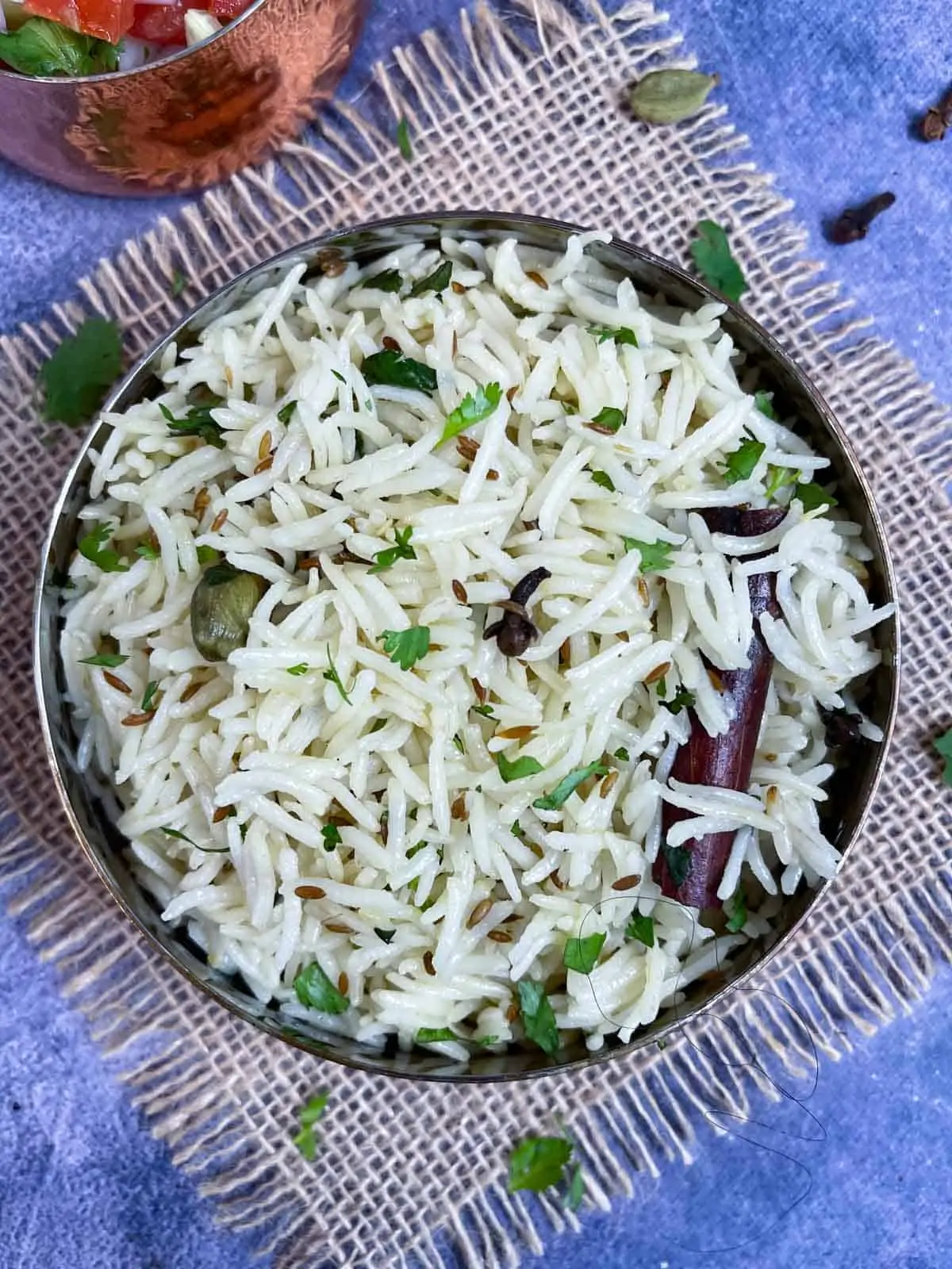 jeera rice served in a copper bowl garnished with cilantro